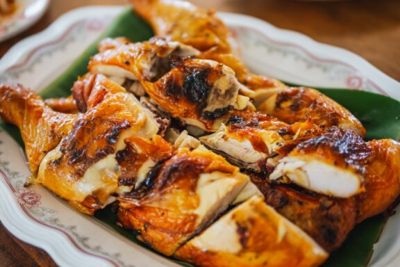 homemade gai yang, Thai style grilled chicken. Fried chicken on banana leaves. Crispy Grilled Chicken are considered to be the perfect pairing. Fried chicken. Thai food.