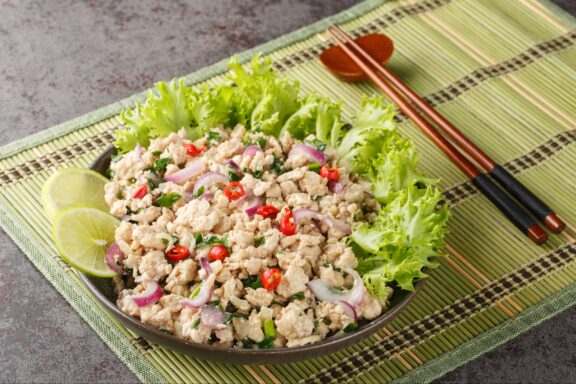 Larp or Laab gai or larb gai spicy salad breast chicken with herb closeup on the plate on the table.