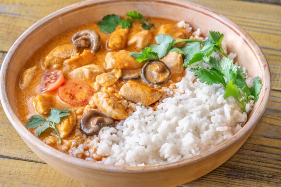 Bowl of chicken red curry on wooden background