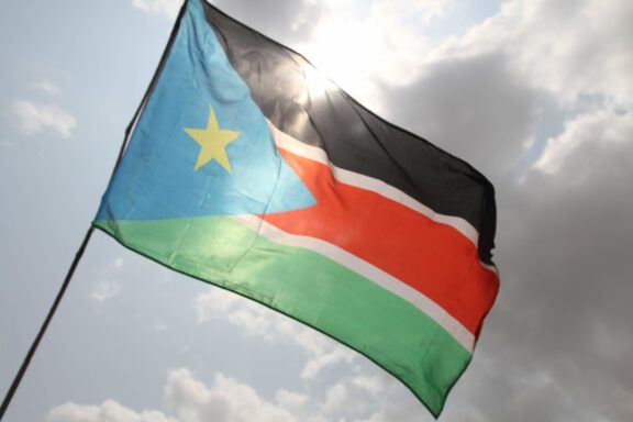 Flag of South Sudan waving against a cloudy sky.