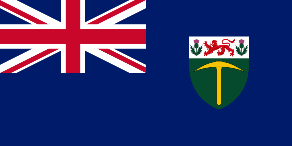 Flag of Southern Rhodesia with a dark blue background, the Union Jack in the top left corner, and a shield featuring a lion and thistles on the right side.