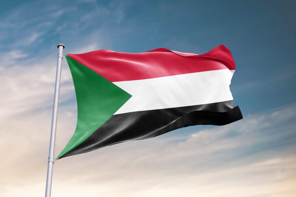 Flag of Sudan waving against a cloudy sky.