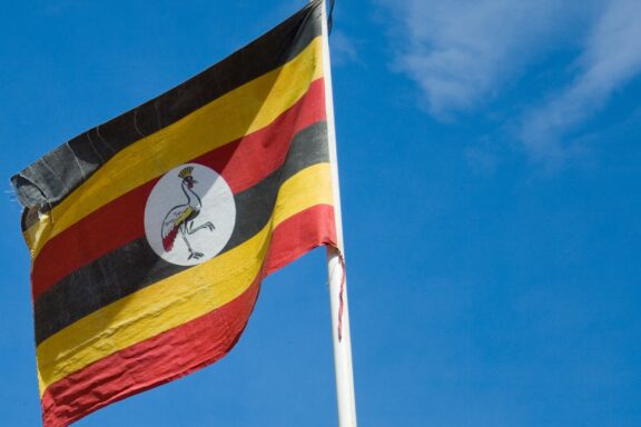 Ugandan flag waving against a clear blue sky.