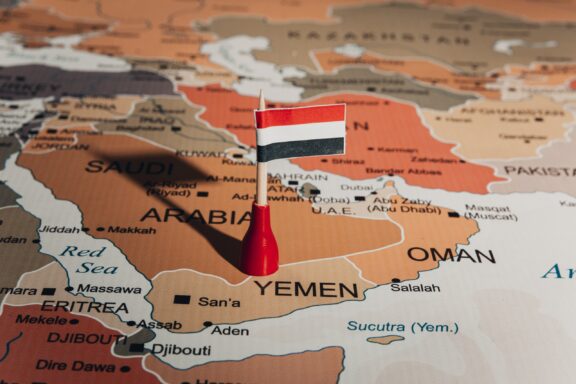 A miniature flag of Yemen placed on a map highlighting the country's location with surrounding nations labeled.