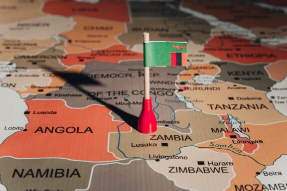 A pin with the flag of Zambia placed on a map at the location of the country.