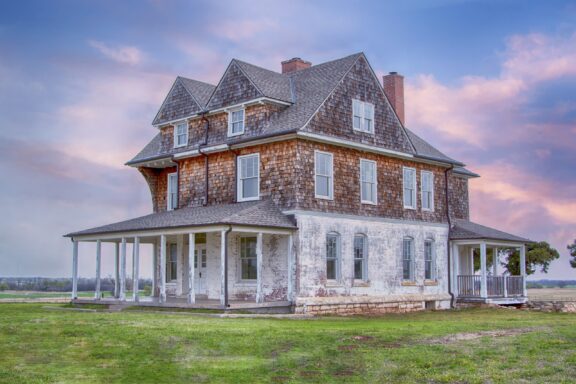 A large, old wooden building stands in a field at Fort Reno.