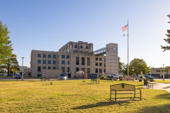 An American flag stands next to the stone courthouse in Enid.