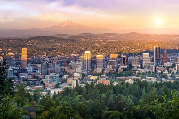 A view of Portland, Oregon from atop a hill. Mount Hood stands in the distance. 