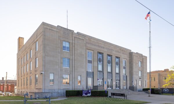 A street-level view of the Pottawatomie Courthouse and the American flag flying in front.