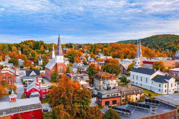 Aerial view of a quaint New England town with historic architecture and colorful autumn foliage.