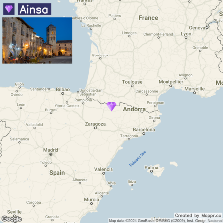 A map highlighting the location of Aínsa in Spain, with a small picture insert of a quaint historical village at night, showcasing stone buildings and outdoor seating near a square.