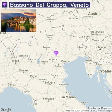 A map showing the location of Bassano Del Grappa in the Veneto region of Italy with a photo inset of the town at dusk, featuring illuminated buildings along the riverbank.