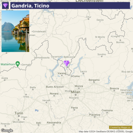 An overlaid image on a map showing a location named "Gandria, Ticino," with a small visual insert of a serene lakeside view of buildings reflected in the water. The map displays surrounding geographic details and towns in the area, with water bodies and borders discernible.