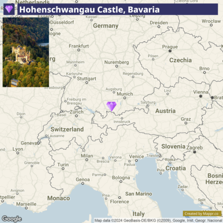 A map showing the location of Hohenschwangau Castle in Bavaria, Germany, with an inset photograph of the yellow castle nestled among green trees. Major surrounding cities and countries are visible, including Munich and parts of Switzerland, Austria, and Czechia.