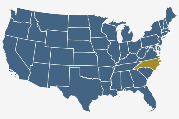 A stylized map of the United States with all states outlined in dark blue except for one highlighted in yellow on the east coast.