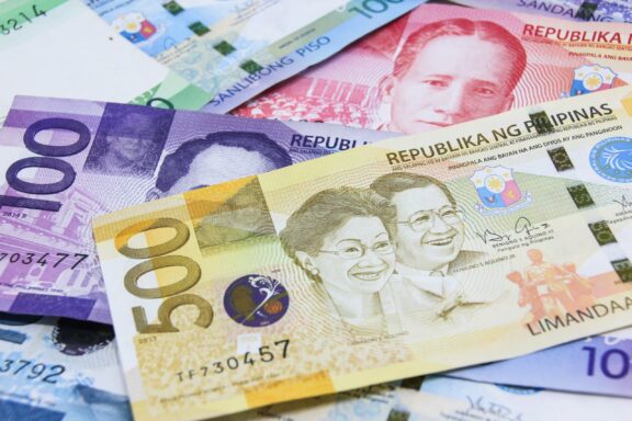 A close-up of various Philippine peso banknotes spread out, showcasing different denominations and designs.