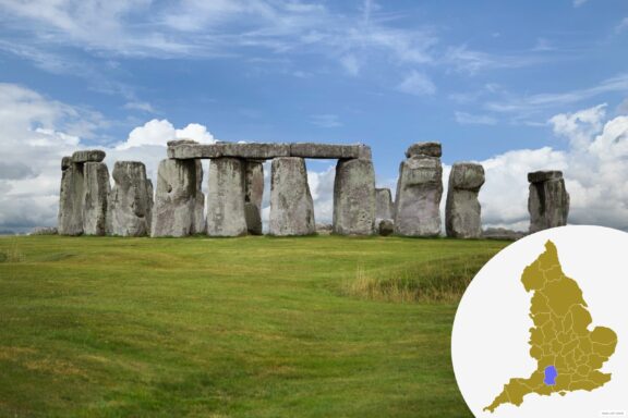 Stonehenge, a prehistoric monument of standing stones with a grassy field in the foreground and a blue sky with clouds above, with an inset map of the United Kingdom highlighting the location of the monument in the lower right corner.