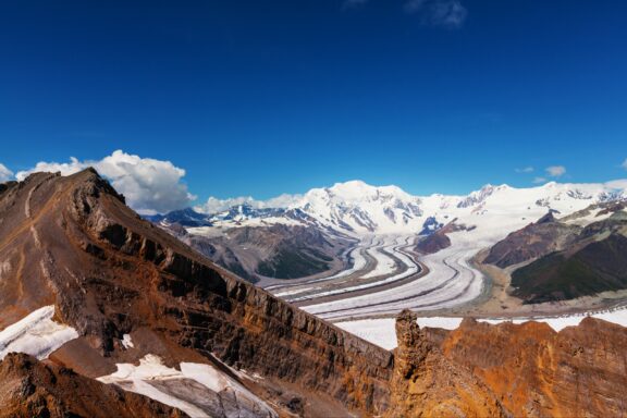 A panoramic view of a rugged mountain landscape with a prominent glacier in the largest national park in the US.