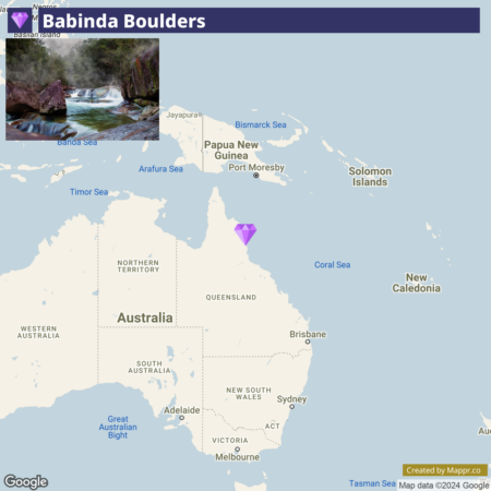 A map highlighting Babinda Boulders in Queensland, Australia, with an inset photo showcasing a serene waterfall and large rocks at the site. Nearby geographical labels include Papua New Guinea, Solomon Islands, and various seas, with Australian cities like Brisbane and Sydney marked on the map.