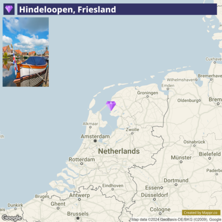 A map highlighting Hindeloopen, Friesland, in the Netherlands with an inset image showing a traditional boat and historical buildings beside a waterway under a clear blue sky.