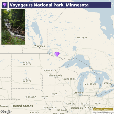 A map highlighting Voyageurs National Park in Minnesota, with parts of the US and Canada visible, including Winnipeg and the Great Lakes. A purple map pin marks the park's location, and an inset photo shows a forested area with a stream and fallen logs.