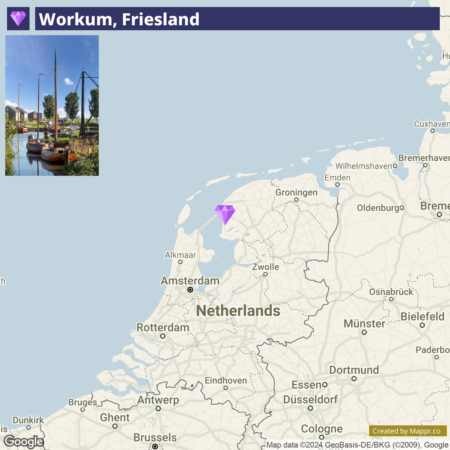 A screenshot of an interactive map highlighting the location of Workum in Friesland, Netherlands, with an inset photograph on the top left corner showing a scenic view of boats moored in a canal with greenery and houses in the background.